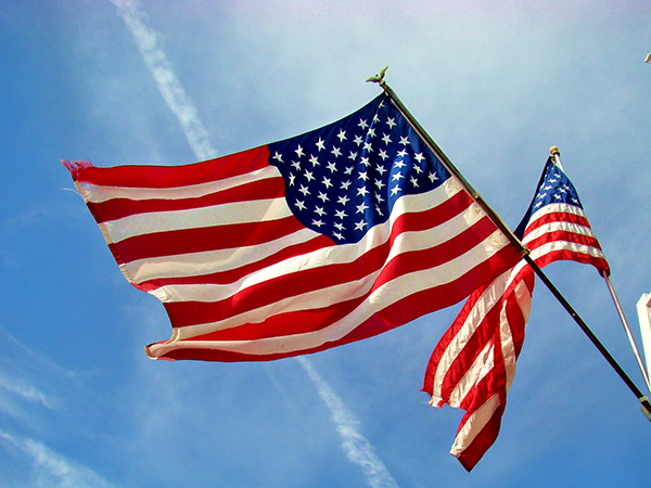 Two American flags against a blue sky