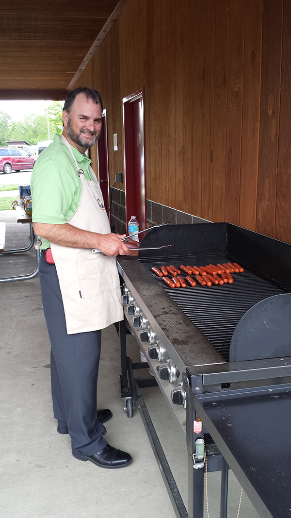 A Socketeer smiles at the camera while grilling hotdogs